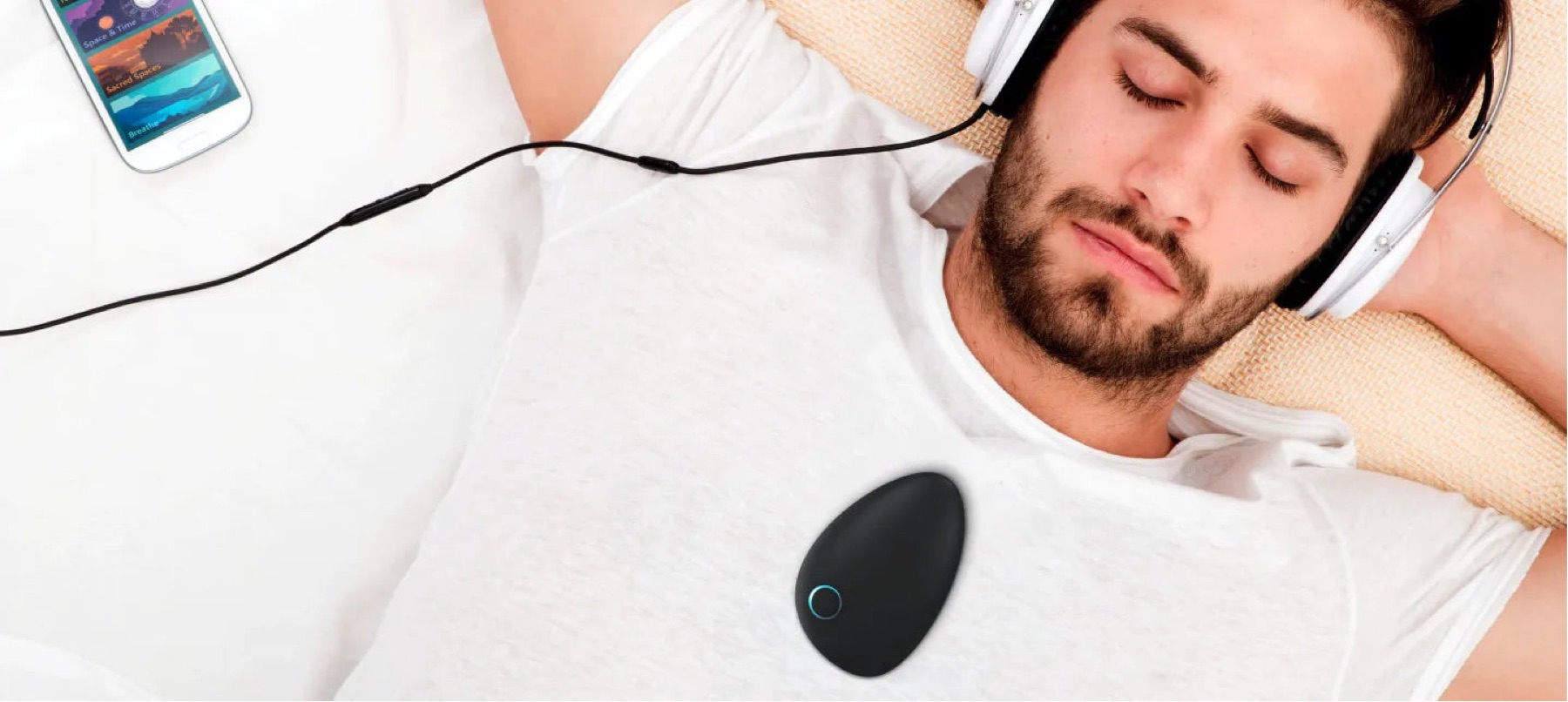 The Sensate device resting on someone's chest while they lie down with headphones